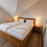 Schlafzimmer mit Doppelbett, zwei Nachttischen und einer Kleiderschrankwand.
