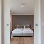 Schlafzimmer mit Doppelbett, Holzboden und grauer Wand.