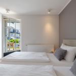 Schlafzimmer mit Bett, Fenster und Kleiderschrank. Blick auf Garten und Straße.