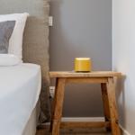 Schlafzimmer mit Bett, Holztisch und gelber Lampe