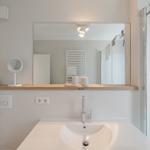 Badezimmer mit Waschbecken, Spiegel und Dusche