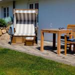 Terrasse mit Liegestuhl, Tisch und Stühlen vor einem Haus