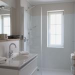 Badezimmer mit Dusche, Waschbecken und Fenster.