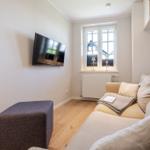 Wohnzimmer mit Sofa, Fernseher und Fenster