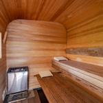 Sauna mit Holzbank, Heizung und Fenster zur grünen Außenwelt.