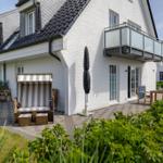 Wohnhaus mit Balkon, Strandkorb und Terrasse im Garten.