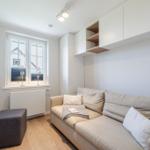 Wohnzimmer mit Sofa, Fenster, Fernseher und Schrank.