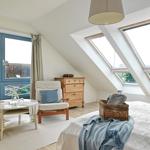 Schlafzimmer mit Dachschräge, Fenster und Bett.