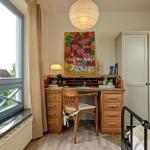 Schreibtisch mit Stuhl, Wandbild und Kleiderschrank neben Fenster mit Blick nach draußen.