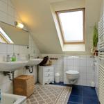 Badezimmer mit Dachschrägen, Dusche, Toilette und Waschbecken.
