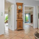 Hausflur mit antikem Standuhr, Türöffnungen zu Wohnräumen und Terrasse.