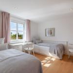 Zimmer mit zwei Betten, Schreibtisch und Fenster mit Blick auf Grünfläche.