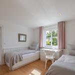 Zwei Betten, Schreibtisch und Fenster mit rosa Vorhängen.