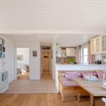 Wohnbereich mit Essbereich, Küche und Schlafzimmer im Hintergrund.