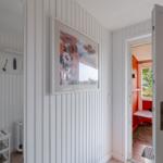 Haus mit weiß verkleideten Wänden, Bild an der Wand und Tür zum Außenbereich.