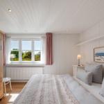 Schlafzimmer mit Bett, Kleiderschrank und Fenster zum Garten.