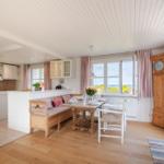 Essbereich mit Holztisch, Sitzbank und Blick aufs Meer.