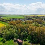 Holzhaus im Wald mit Blick auf Felder und Dorf.
