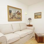 Ein Wohnzimmer mit einem cremefarbenen Sofa, zwei Bildern an der Wand und einem Holzboden.