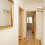 Flur mit Holzboden, goldgerahmtem Spiegel und Bildern an der Wand.