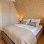 Schlafzimmer mit Doppelbett, Holzboden und gemusterter Wand