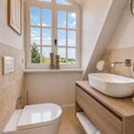 Badezimmer mit Duschbadewanne, Fenster und Holzwaschtisch