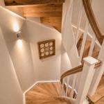 Hölzerner Wendeltreppe mit weißem Geländer und Wandbeleuchtung