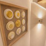 Wanddekoration mit goldenen Kreisen in Holzrahmen neben einer Wandlampe.