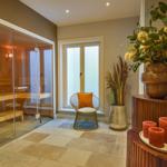 Sauna mit Glaswand, Sitzgelegenheit und Dekoration im Eingangsbereich.
