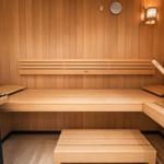 Sauna mit Holzbank, Thermometer und Holzwaschkarre.