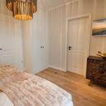 Schlafzimmer mit Bett, Holzboden, Schrank, Fernseher und goldener Fischfigur.