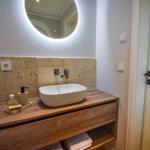Badezimmer mit Waschtisch, Spiegel und Handtuchregal.
