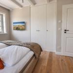 Schlafzimmer mit Bett, Kleiderschrank und Fenster. Holzboden und Wandbild.