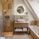 Badezimmer mit Dusche, Badewanne und Waschtisch unter Dachschrägen.