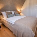 Schlafzimmer mit Doppelbett, Holzboden und zwei Nachttischen mit Lampen.