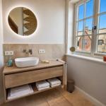 Badezimmer mit Waschtisch, Spiegel und Fensterblick auf Dächer