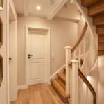 Hausflur mit Holztreppe, Spiegel und Wanddekoration.