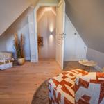Dachgeschosszimmer mit Sessel, Holzboden und Tür zum Flur.