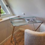 Schreibtisch mit Stuhl unter Dachschräge, Fenster und Holzskulptur