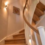Eine Treppe mit Holzstufen und weißem Geländer führt nach oben. An der Wand hängt ein gerahmtes Kunstwerk.