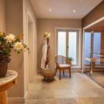 Saunaraum mit Glaswand, Stuhl und Blumenarrangement an der Wand.
