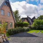 Haus mit Backsteinfassade und Dach aus Schiefer. Gartenweg mit Kies und Steinmauern.