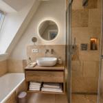 Badezimmer mit Dusche, Badewanne und Waschtisch unter Dachschrägen