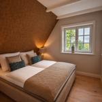 Schlafzimmer mit Dachschrägen, Bett, Fenster und Wandbild.