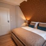 Schlafzimmer mit Bett, Wand-TV und Holzboden. Die Wand hinter dem Bett ist braun gemustert.