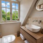 Badezimmer mit Duschwanne, Fenster und Holzregal. 