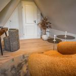 Dachgeschosszimmer mit Schreibtisch, Sessel und Couch. Holzboden und Pflanze sichtbar.