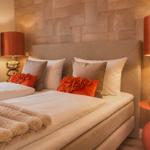 Ein Bett mit Kissen und Decke, zwei Nachttische mit Lampen und eine Wand mit Paneelen.