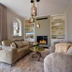 Wohnzimmer mit Sofa, Sessel, Kamin und Bücherregalen.