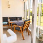 Terrasse mit Holztisch, Stühlen und Sitzbank. Durchgehende Glasfront zum Garten.